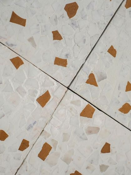 A close-up of the intersection of four leather-finish tiles, highlighting the matte surface and the natural variation in the stone chips.