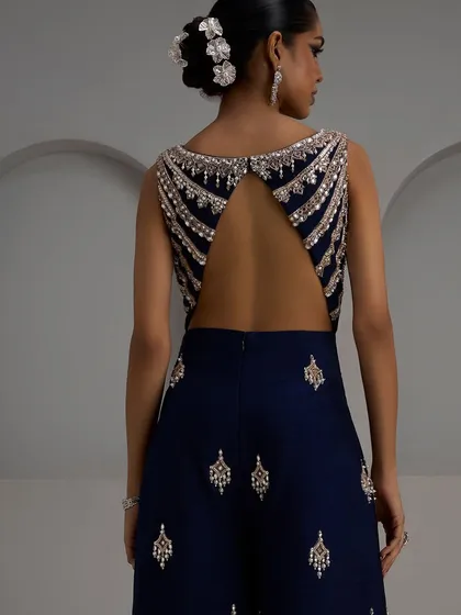 The beauty of a garment is often in the details that are revealed with movement. This intricately embroidered open-back blouse pairs drama with elegance, making every turn a statement. It’s a perfect piece for a cocktail party or sangeet.