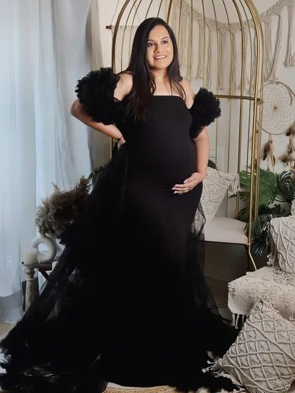 A powerful and confident pose in a striking black gown with tulle details. The mom-to-be stands proudly in our boho-chic studio corner, creating a look that is both elegant and modern.