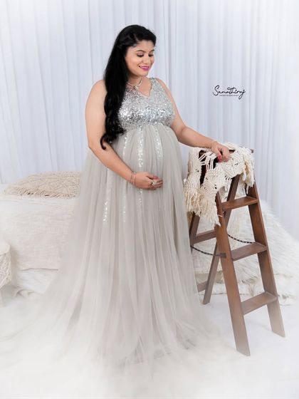 A serene portrait in a silver sequined gown. The soft, dreamy setup with a bed and ladder prop creates a cozy and intimate atmosphere for this indoor shoot.