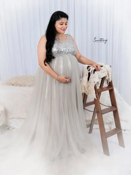 A serene portrait in a silver sequined gown. The soft, dreamy setup with a bed and ladder prop creates a cozy and intimate atmosphere for this indoor shoot.