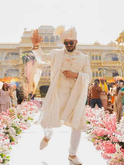 The groom makes a grand, dancing entrance down the floral-lined aisle.