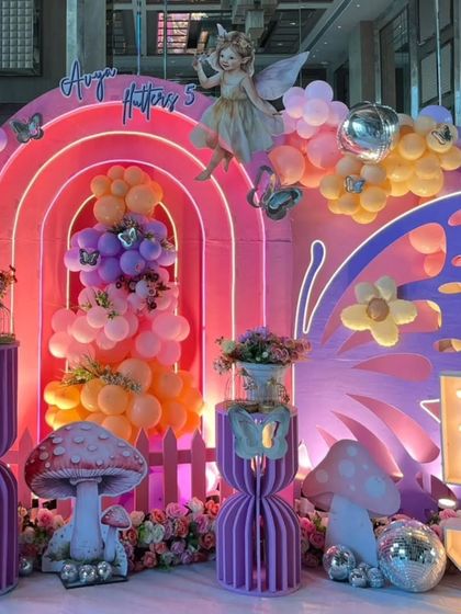 A close-up of the enchanted fairy party, showing the layered rainbow backdrop, a floating fairy prop, and butterfly details.