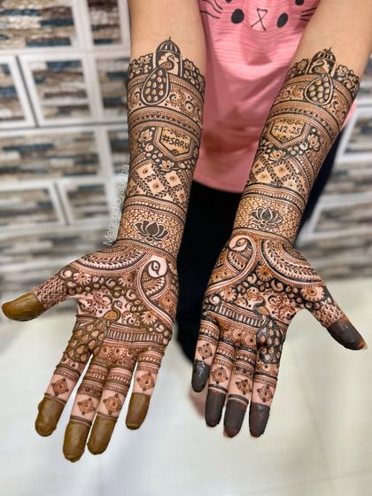 This engagement mehendi includes the couple's hashtag '#SARU' and their special date, '2-12-25', alongside classic peacock and lotus designs.