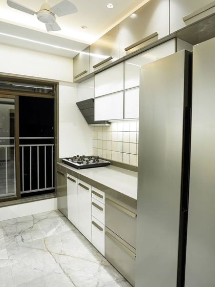 This parallel kitchen design features a clean, modern aesthetic with white and grey cabinets. The layout provides ample counter space and integrates the refrigerator seamlessly.