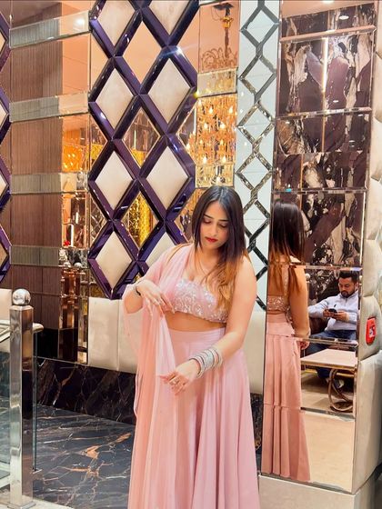 Adjusting the dupatta of the pink lehenga. This action shot adds movement and a touch of grace to the photo.