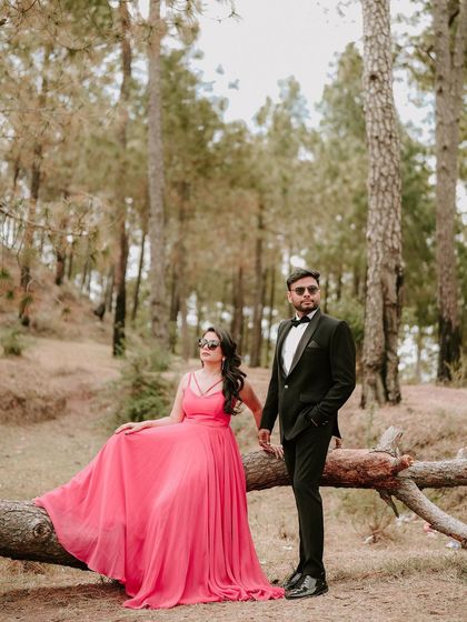 A stylish portrait of the couple posing by a fallen tree, their formal attire contrasting beautifully with the rustic forest, creating a modern yet natural pre-wedding photo.