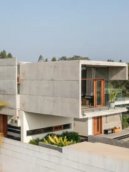 The side elevation of The Quarry House reveals a complex arrangement of stacked and cantilevered volumes. The design uses exposed concrete to create a raw, monolithic aesthetic that is softened by the lush tropical planting.