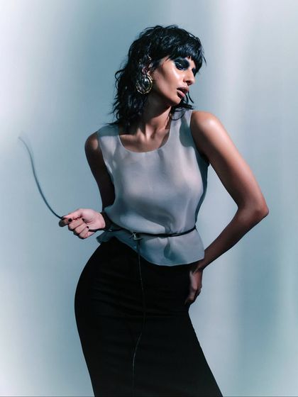 A close-up that captures the model's expression and the subtle details of the outfit, including the thin belt. The lighting creates a soft, ethereal glow on the skin.