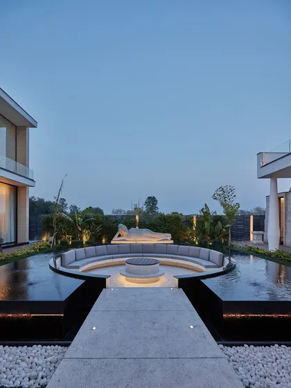We craft outdoor spaces that serve as tranquil retreats for reflection and connection. This sunken lounge, centered around a fire pit and watched over by a serene Buddha sculpture, is enveloped by a still water body. It is a perfect place to meditate and find balance, transforming the garden into a sanctuary.