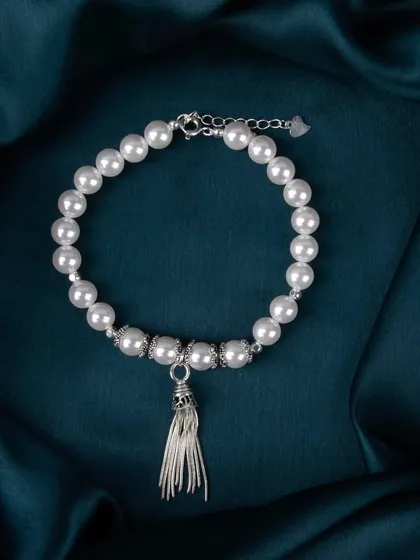 A pearl bracelet with a silver tassel charm.