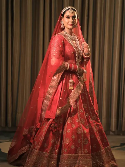 A full-length portrait of this bride in her timeless red lehenga. The makeup was crafted to exude elegance and grace, with a radiant glow that enhances her natural beauty.