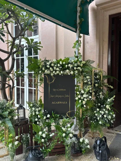 A closer view of the welcome signage, showing the detail of the floral arrangement. We use a mix of white roses, baby's breath, and assorted greenery to create a lush and inviting display.