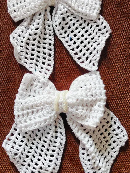 Two elegant white lacy bows, one with a simple pearl strand in the center and the other with a single pearl. They are perfect for a classic, graceful look.