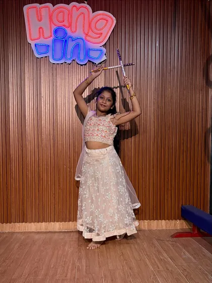 A smiling student in a light-colored lehenga poses with her dandiya. Our goal is to create happy memories and a lifelong love for dance.