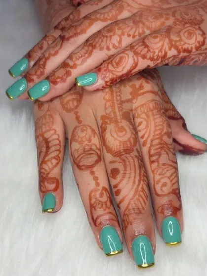 A beautiful teal manicure with gold chrome tips, perfectly complementing henna-adorned hands.