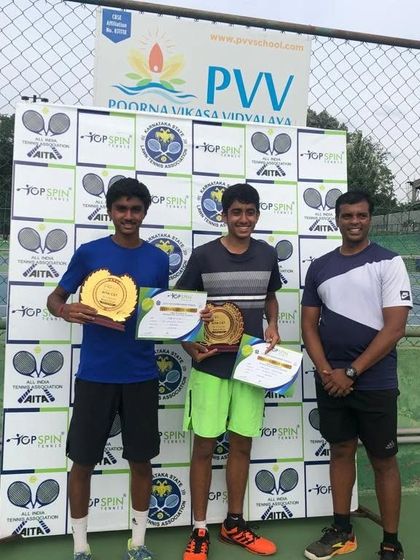 A full-view shot of the U-18 doubles winners with their coach and their awards.