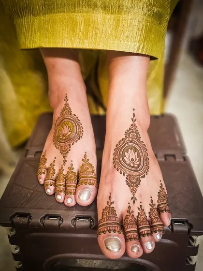 Mehendi for the feet is an essential part of the bridal look. This elegant design features a lotus motif enclosed in a decorative frame, with detailed patterns on the toes, creating a balanced and beautiful look.