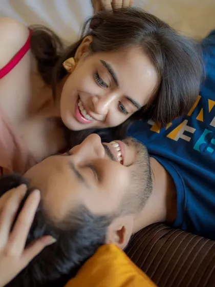 A playful and relaxed moment of a couple lying down and laughing together. This casual and intimate perspective captures the comfort and fun of their relationship.