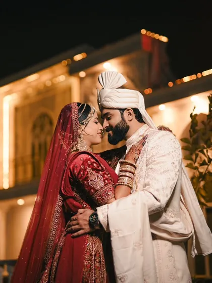 A romantic night portrait of a couple in a loving embrace, with the warm lights of the venue creating a beautiful bokeh background.