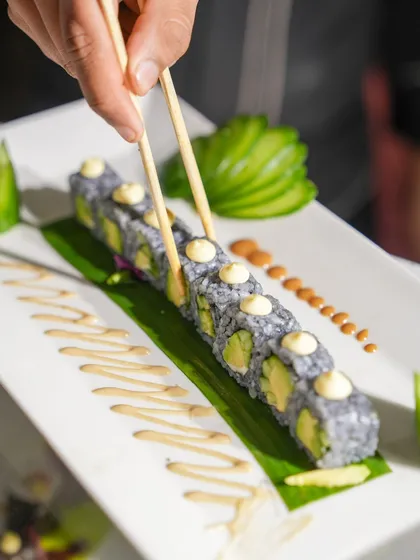 A close-up of our charcoal avocado sushi rolls, beautifully arranged and dotted with mayonnaise. A visually stunning and delicious offering from our Pan-Asian menu.