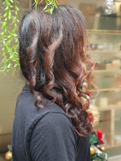 A side profile of a men's style, showcasing expertly crafted curls and a rich, subtle colour that adds dimension and character to long hair.