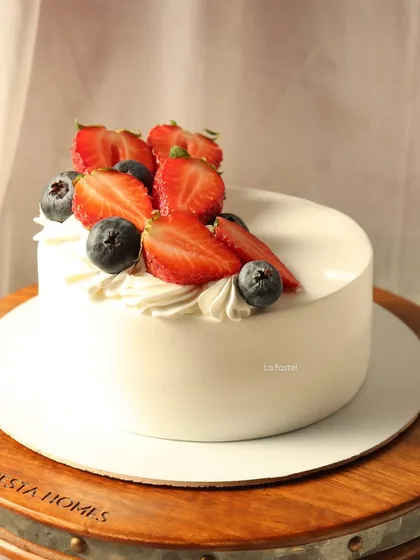 A minimal Korean-style cake topped with fresh strawberries and blueberries.