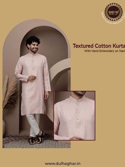 A classic textured cotton kurta in a soft pink. The hand embroidery on the neck adds a touch of craftsmanship. This is a great choice for a comfortable yet stylish festive look.