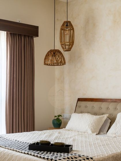 The same master bedroom in natural daylight. The soft light highlights the textures of the wall, the tufted headboard, and the rattan pendant lights, creating a serene and airy atmosphere.