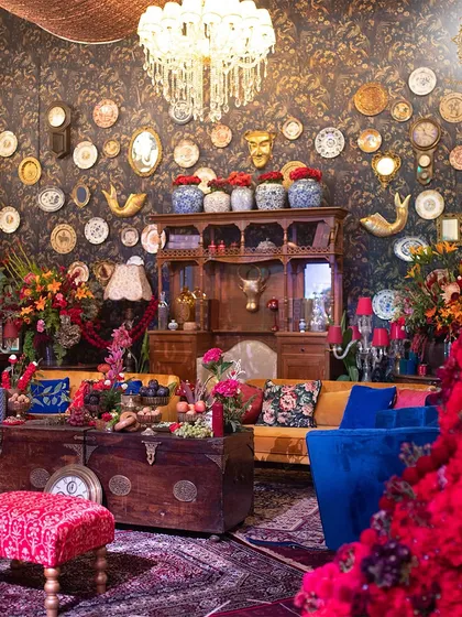 This vignette features a curiosity cabinet-style wall with decorative plates, masks, and animal figures. A large wooden chest serves as a coffee table, enhancing the collected, well-traveled feel of the space.