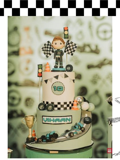 The F1-themed birthday cake for Vihaan, complete with a race car driver, checkered flags, and a trophy. The cake is always a central part of the theme.