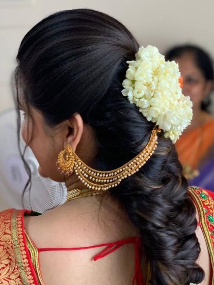 A side view of a traditional messy braid, showing how the jasmine flowers and gold earring chain (maatal) integrate beautifully with the hairstyle.