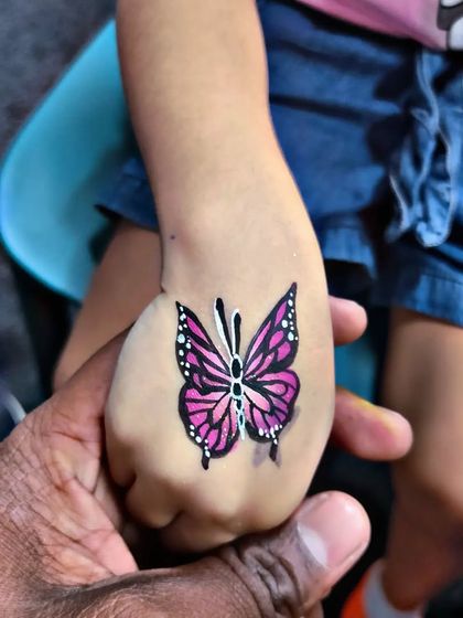 A detailed monarch butterfly painted on the back of a child's hand.