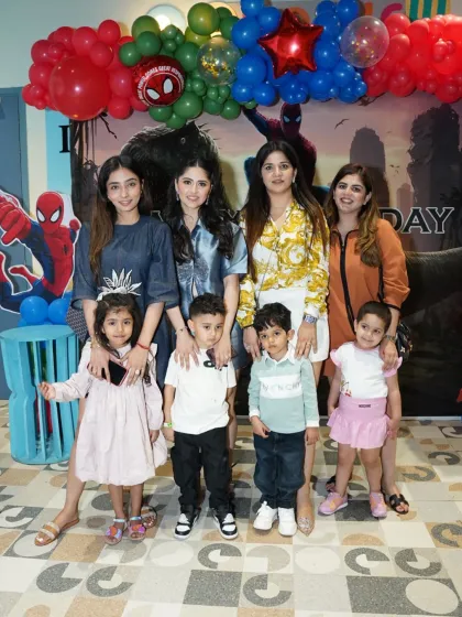A happy group of family and friends gathers for a photo at a Spider-Man themed birthday party. The balloon arch and backdrop tie the whole celebration together.