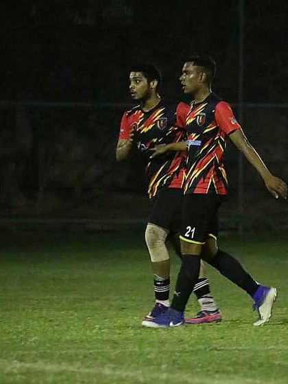 Two of our players in sync on the field during a night match, demonstrating teamwork and communication.