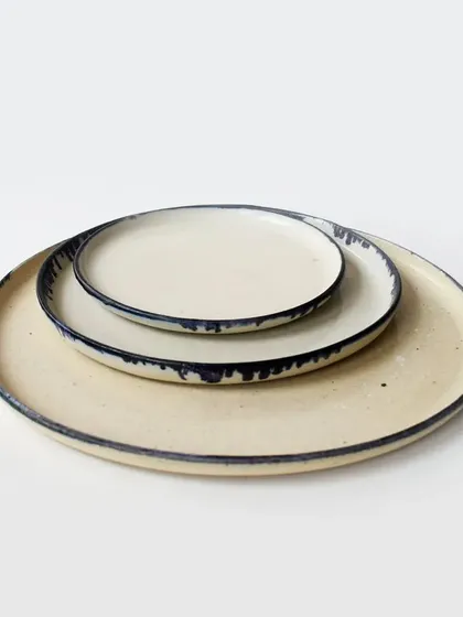 A stack of our dinner and side plates, showing how you can layer different sizes to create a complete and cohesive table setting. The dripping glaze effect on the rim is a signature detail.