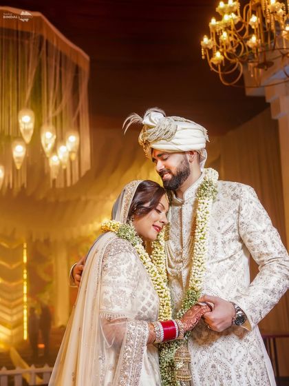 A tender moment between the newly married couple. The groom's gentle forehead kiss and their embrace convey a sense of comfort and deep affection.