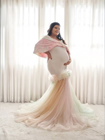 A full-length view of the rainbow pastel gown. The mermaid-style fit is made of comfortable stretch fabric, while the tulle trail adds a splash of color and fun.