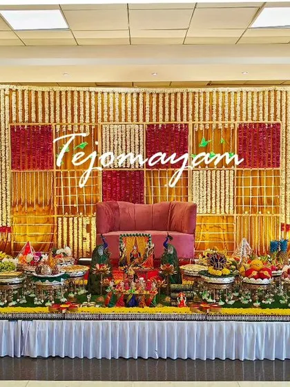 A baby shower setup with a checkered backdrop of red, white, and gold flowers. The symmetrical arrangement of plates and lamps creates a balanced and visually pleasing display.