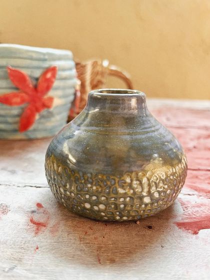 Look at these beautiful little wares from a beginner's course. She created a lovely marbled mug, a textured vase, and a carved luminary with a rich, rustic glaze.