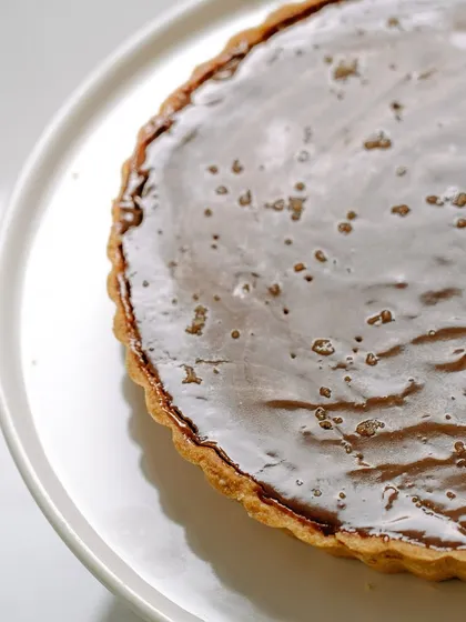 A close-up of our glossy salted caramel chocolate tart. The smooth, rich filling and buttery crust make this an irresistible dessert for any chocolate lover.