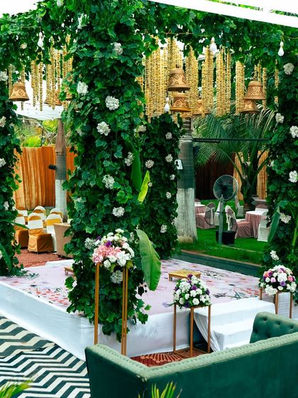 Another angle of the green mandap, showing the intricate details of the hanging bells and the clean, elegant stage setup. This design is perfect for a nature-inspired, traditional wedding.