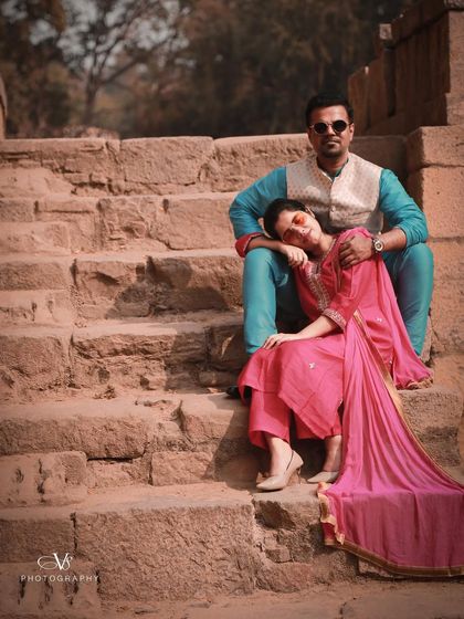 A relaxed and regal pre-wedding portrait of a couple in traditional attire, seated on ancient stone steps.