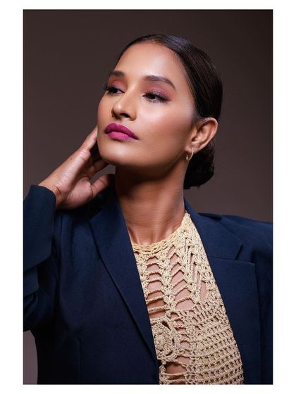 A sophisticated studio portrait of a model in a blazer and a crochet top. The lighting is soft and flattering, creating a professional and high-end look.