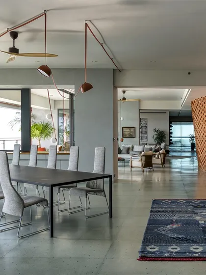 The open-plan dining and living area of Sampurna Residence is defined by a textured brick wall and polished concrete floors, creating a sophisticated yet comfortable urban home.