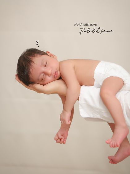 A creative pose showing the baby sleeping peacefully while being held up by a parent's hands. This shot emphasizes how small and precious they are.