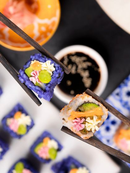 A playful shot of two different sushi rolls crossing chopsticks, showcasing the variety I offer.