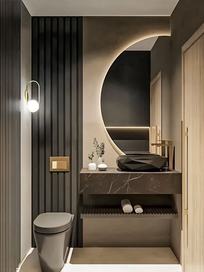 A dramatic and moody bathroom featuring dark, textured walls and a unique, half-moon backlit mirror. The geometric black sink and floating marble-topped vanity add to the luxurious, contemporary feel.