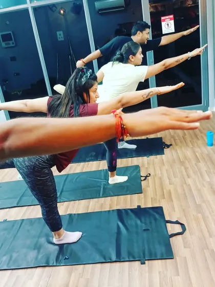 Students holding Virabhadrasana III (Warrior III Pose) in a group setting. This challenging balance pose strengthens the entire body and improves focus.