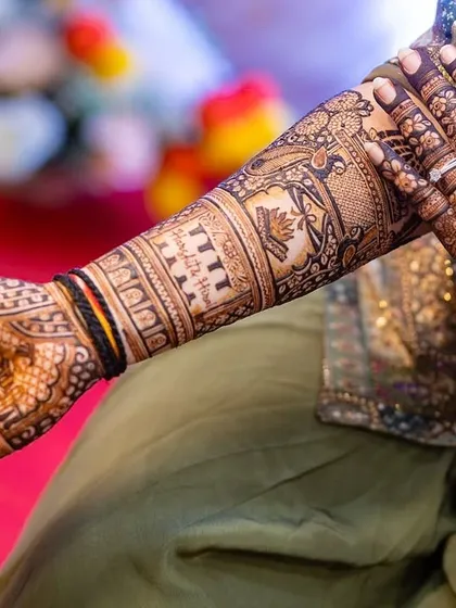 A close-up of a stunning bridal arm, showcasing intricate details like peacocks, floral bands, and personalized elements for a one-of-a-kind design.